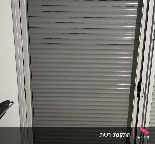 תריס אלומיניום סגור במסגרת חלון לבנה